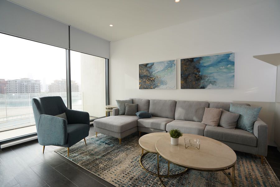 Modern open-plan living room with premium sofa set and artistic wall decor by Almoayyed Contracting Group.