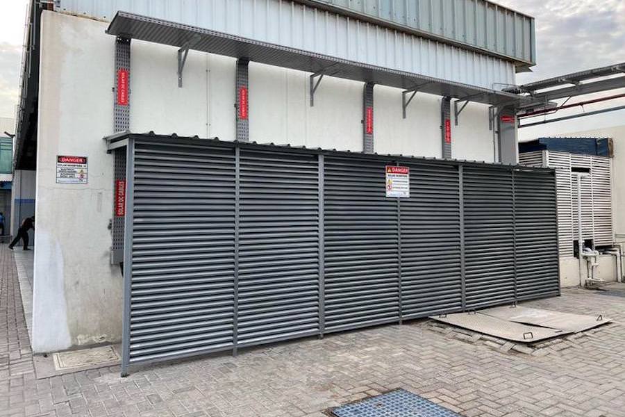 Industrial equipment housing and protective fencing for a technical site by Almoayyed Contracting Group.