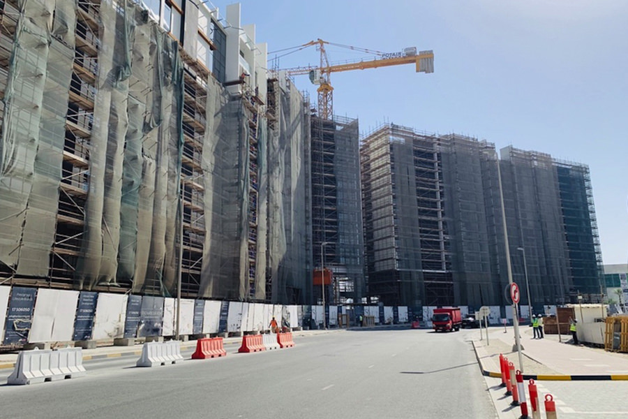 Progress shot of multi-story building construction featuring tower cranes and Almoayyed Contracting Group expertise.