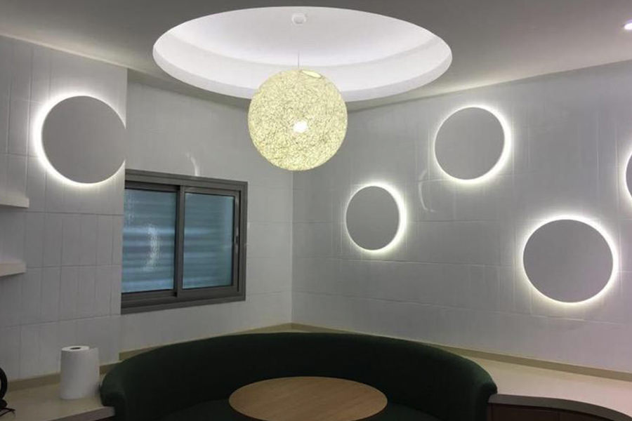 Modern office reception area with circular wall lighting and custom seating by Almoayyed Contracting Group.