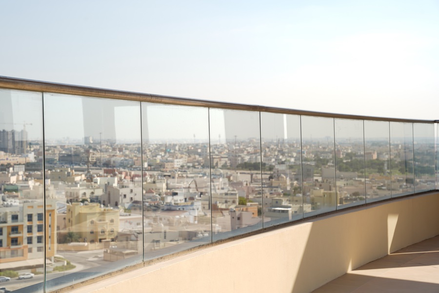View of the city skyline through glass balcony railings installed by Almoayyed Contracting Group.
