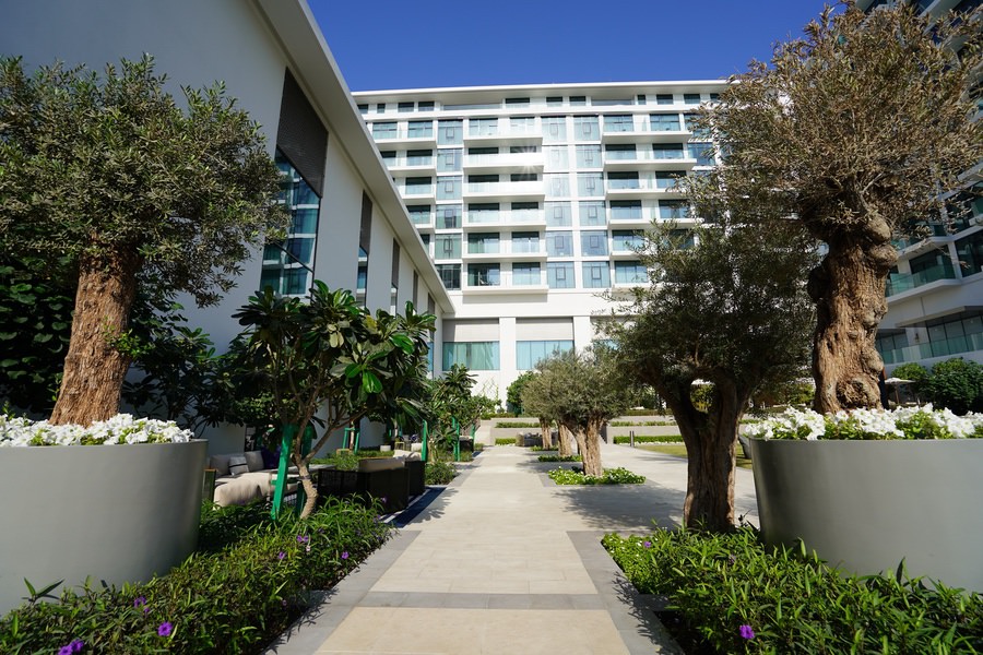 Paved walkway surrounded by lush garden landscaping at a residential development by Almoayyed Contracting Group.