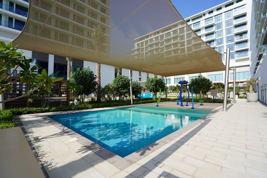 Residential swimming pool and shaded leisure area featuring custom pergolas by Almoayyed Contracting Group.