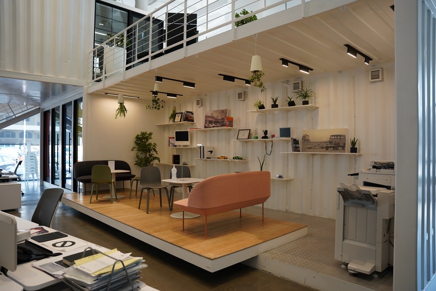 Creative open-plan office mezzanine with modern seating and shelving by Almoayyed Contracting Group.