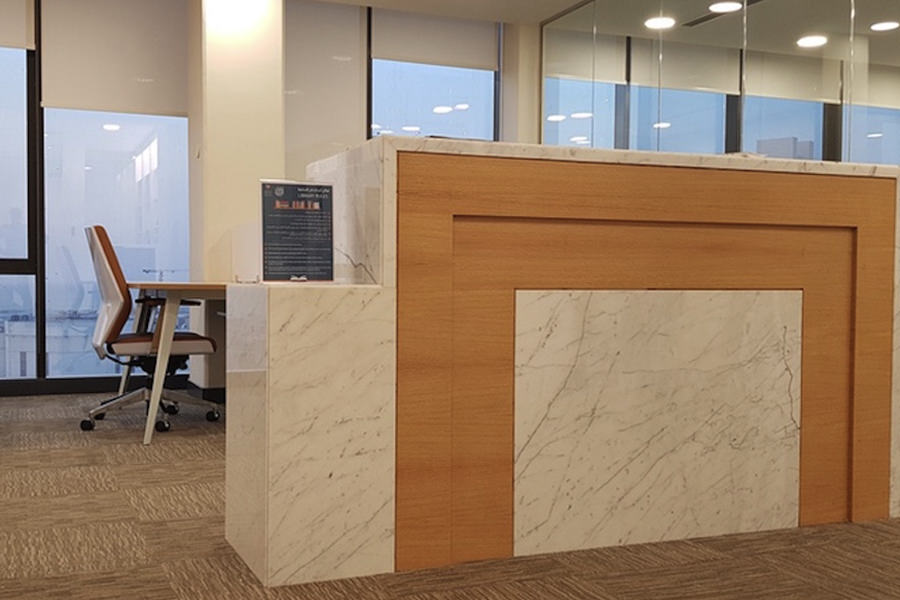 Modern marble and wood reception desk interior fit-out by Almoayyed Contracting Group.