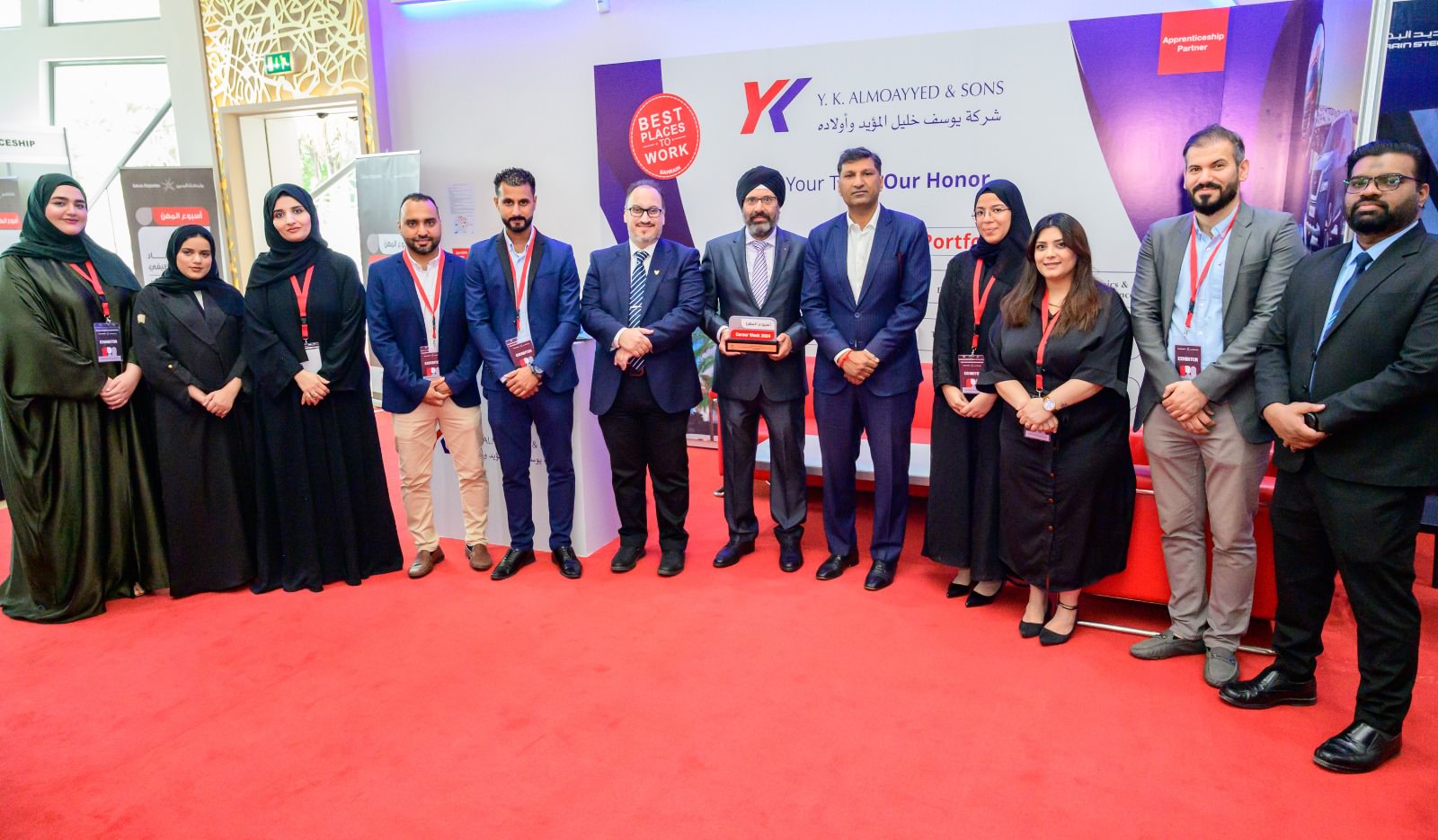 Almoayyed Contracting Group team members posing together at a formal red-carpet event.